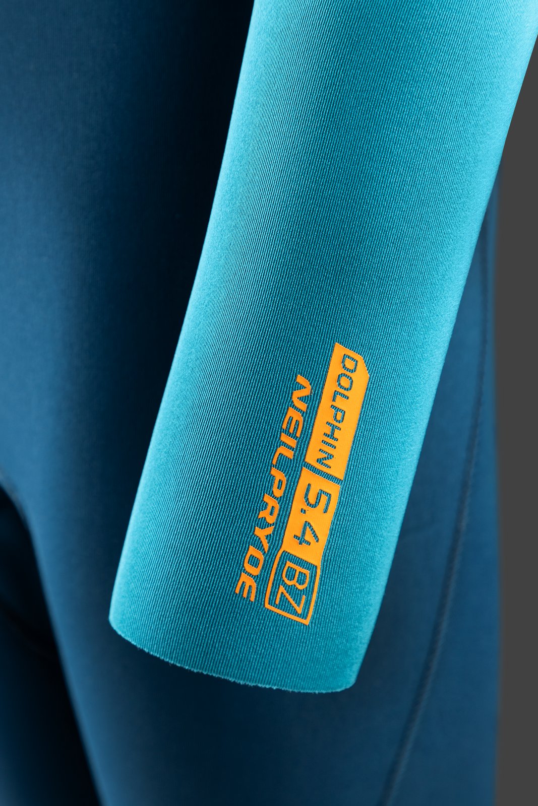 NeilPryde Dolphin Youth 5/4 GBS BZ 2025 gyermek neoprén ruha ujjának részlete narancssárga felirattal