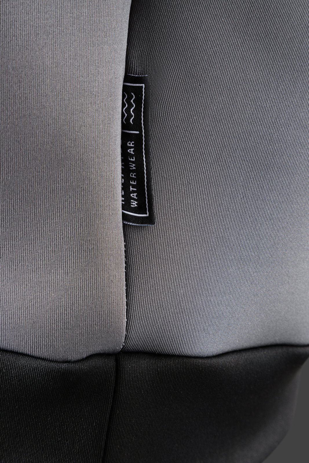 A Neo Hoodie 2026 neoprén kapucnis felső sötétszürke anyagának és márkajelzésének közeli részlete