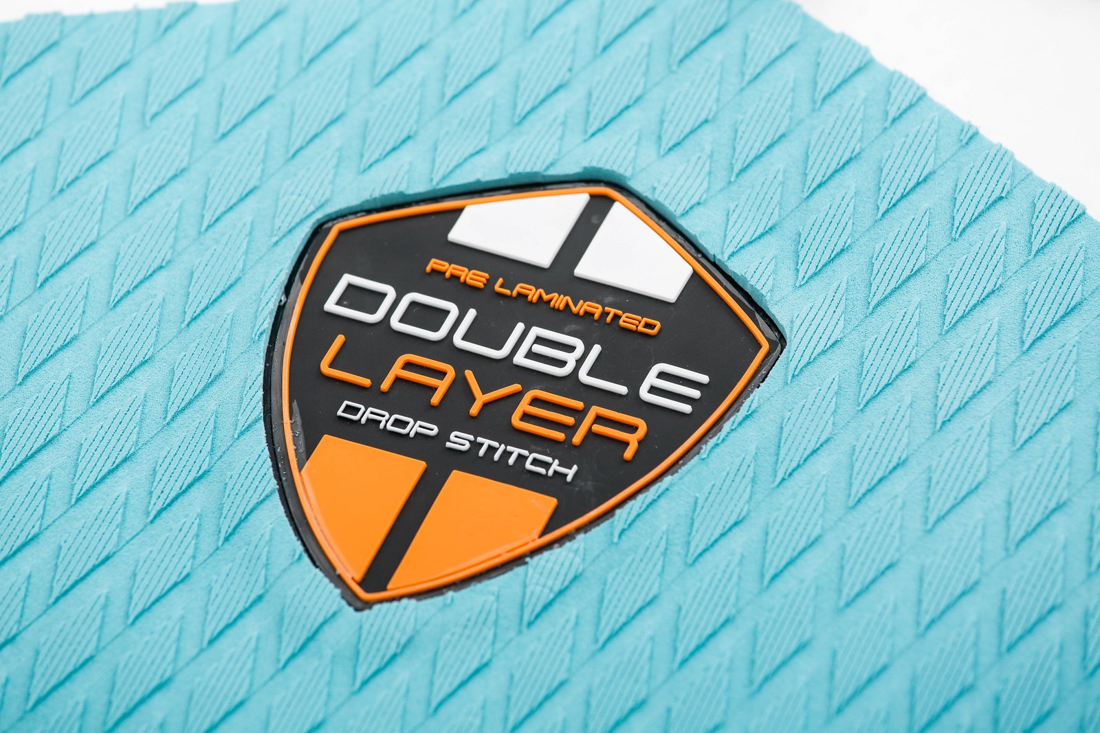A Venus 5 LE 2025 SUP deszka felületén található Double Layer Drop Stitch technológiát jelző gumírozott logó türkizkék csúszásgátló padon