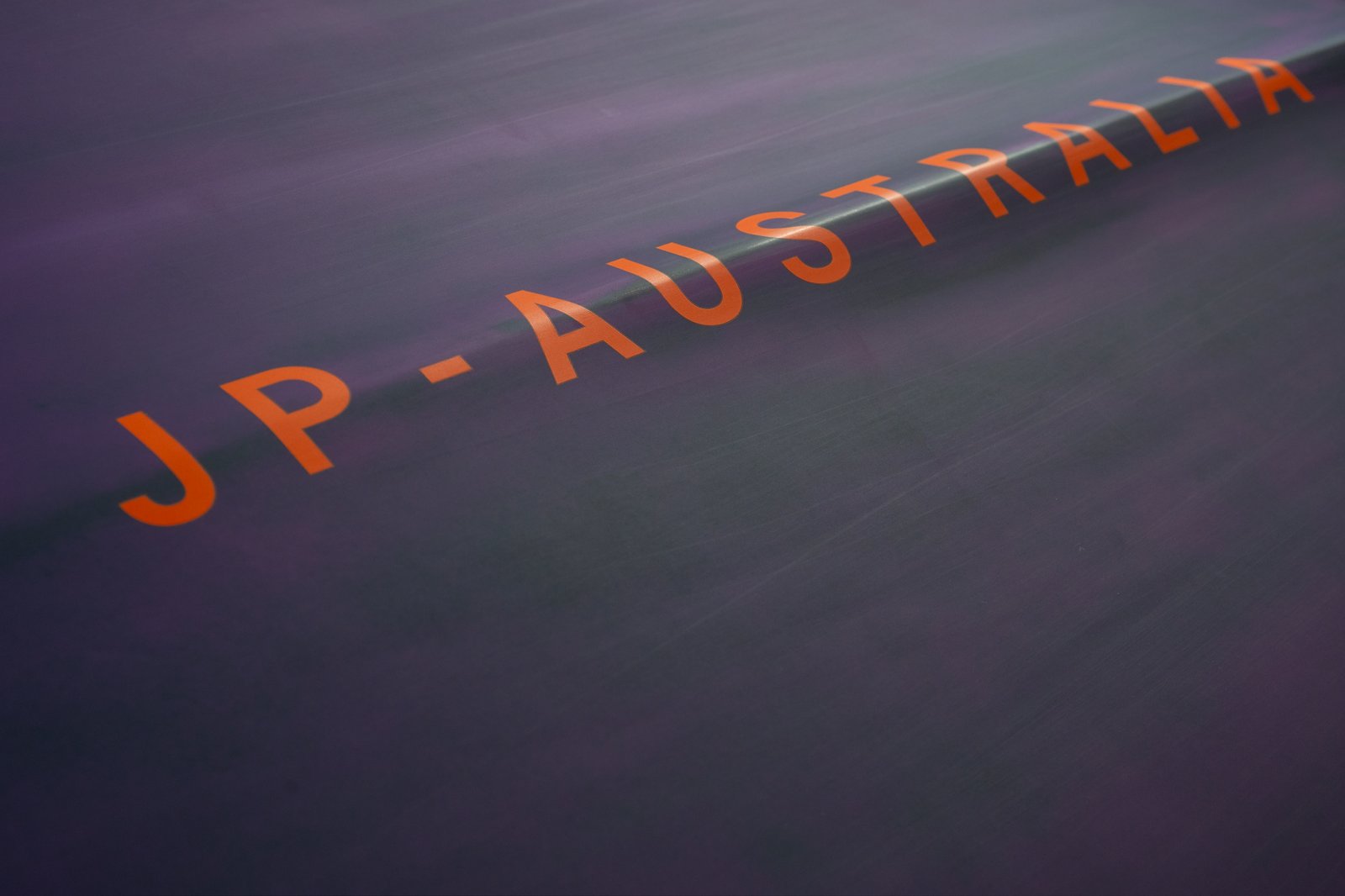 Narancs színű JP-Australia márkafelirat a 2026-os HydroFoil Slalom verseny deck felületén